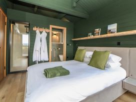 A bedroom with a bed and two robes at The Larch House in Farndon