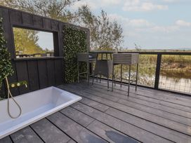 An outdoor area featuring a bathtub and a bar table with stools at The Larch House in Farndon