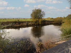 A river with trees and grass along the banks at The Larch House in Farndon