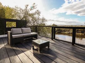 An outdoor seating area with a sofa and coffee table overlooking a river at The Larch House in Farndon