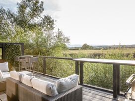 An outdoor patio with a sofa and table overlooking a field at The Larch House in Farndon