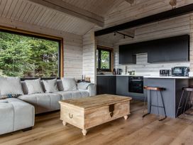 A living room with a sofa and kitchen area at The Larch House in Farndon