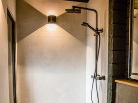 A shower with a black faucet and shower head at The Larch House in Farndon