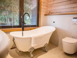 A bathroom with a bathtub and toilet at The Larch House in Farndon