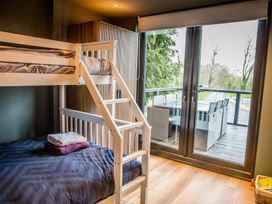 A bedroom with a bunk bed and access to a deck at The Larch House in Farndon