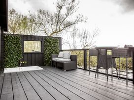 An outdoor area with a couch, bar table and stools at The Larch House in Farndon