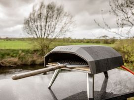 A pizza oven with a wooden peel on a table in an outdoor area at The Larch House in Farndon