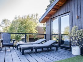 A deck with chairs and loungers at The Larch House in Farndon