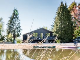 A house near water with trees and kayaks at The Larch House in Farndon