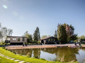 A house by a lake with trees and deck chairs at The Larch House Farndon