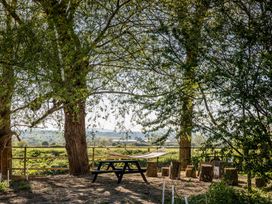 An outdoor area with a table and hammock surrounded by trees at The Larch House Farndon