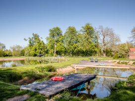 An outdoor area with a pond and dock at The Larch House in Farndon