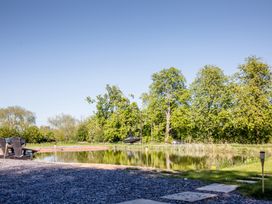 A view of a pond with trees and a boat at The Larch House in Farndon