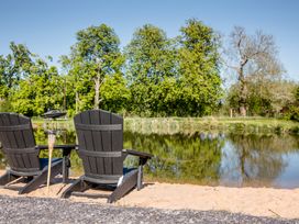 Adirondack chairs by the water in the garden at The Larch House in Farndon