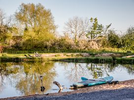 A paddleboard on sandy shore near water with chairs and trees at The Larch House in Farndon