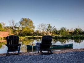 An outdoor seating area by the river with chairs and a canoe at The Larch House in Farndon