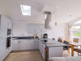 A kitchen with cabinets, sink, and dining area at Cedar 1 Pinewood Retreat