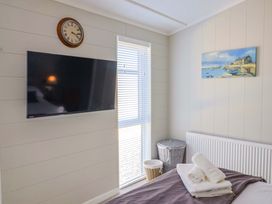 A bedroom with a television and clock at Cedar 1 Pinewood Retreat in Rousdon near Lyme Regis