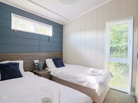 A bedroom with two beds and a window at Cedar 1 Pinewood Retreat in Rousdon near Lyme Regis