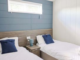 A bedroom with two single beds and a nightstand at Cedar 1 in Pinewood Retreat in Rousdon near Lyme Regis