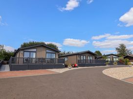 An outdoor view of lodges with decking and gravel at Cedar 1 in Pinewood Retreat in Rousdon near Lyme Regis