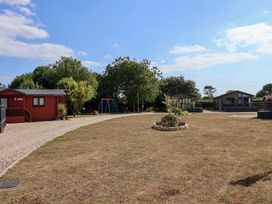 An outdoor area with cabins and a swing set at Cedar 1 Pinewood Retreat in Rousdon near Lyme Regis