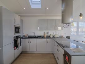 A kitchen with appliances and a clock at Cedar 1 in Pinewood Retreat in Rousdon near Lyme Regis