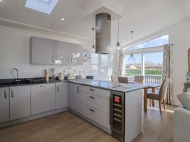 A kitchen with a stove, sink, and dining area at Cedar 1 Pinewood Retreat in Rousdon near Lyme Regis