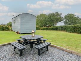 An outdoor space with a table and benches near a shepherd's hut at Llewelyn Ty Croes