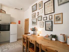 A kitchen with a table and chairs beside a wall with various artworks at Apartment 2 The Bridge at Stanford Hotel near Great Witley