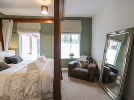 A bedroom with a bed and armchair at Apartment 2 The Bridge at Stanford Hotel near Great Witley