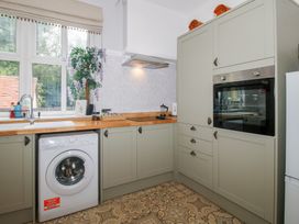 A kitchen featuring a washing machine, sink, oven, and kitchen cabinets at Apartment 1 The Bridge at Stanford Hotel near Great Witley