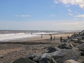 A beach with people walking along the shore at Meadows Park 3 Great Hatfield near Hornsea