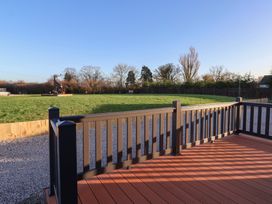 A deck overlooking a grassy area with trees and a sculpture at Meadows Park 4 Great Hatfield near Hornsea