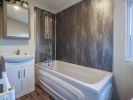 A bathroom with a bath, basin, mirror, and cabinet at Meadows Park 4 in Great Hatfield near Hornsea