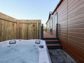 An outdoor area with a hot tub beside a wooden deck at Meadows Park 4 Great Hatfield near Hornsea