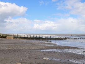 A beach with a wooden pier and waves at Meadows Park 5 Great Hatfield near Hornsea