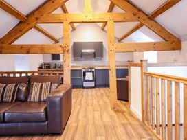 A living room with a sofa and kitchen area at Clegir Bach in Corwen