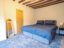 A bedroom with a double bed and mirror at Clegir Bach in Corwen
