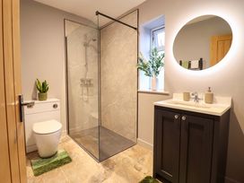A bathroom with a shower, toilet, and vanity cabinet at Clegir Bach in Corwen