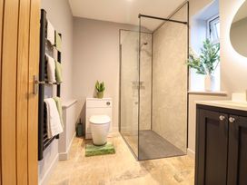 A bathroom featuring a shower, toilet, sink and towels at Clegir Bach Corwen