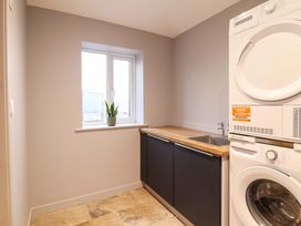 A laundry room with a sink and washer dryer at Clegir Bach in Corwen