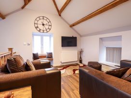 A living room with a clock and television at Clegir Bach in Betws Gwerfil Goch near Corwen