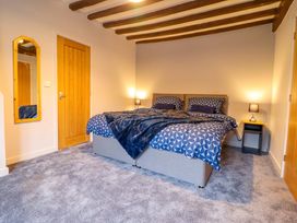 A bedroom with a bed and mirror at Clegir Bach in Betws Gwerfil Goch near Corwen