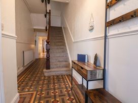 A hallway with a staircase and console table at Mariners Lee