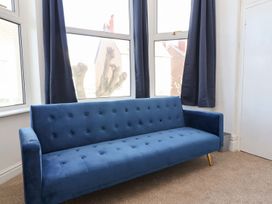 A living room with a blue sofa and curtains at Mariners Lee