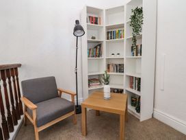 A reading nook with a chair, table, and bookshelf at Mariners Lee in 