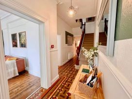 A hallway with a staircase and artworks at Clarence House Llandudno