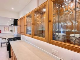 A kitchen with glassware and tableware in cupboards at Clarence House Llandudno