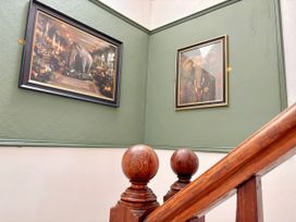 A staircase with framed artworks on a green wall at Clarence House in Llandudno